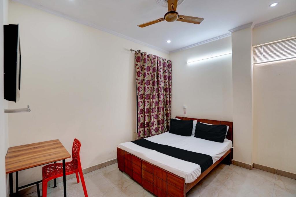 a bedroom with a bed and a table and a ceiling fan at Super OYO OM SAI RAM GUEST HOUSE in Gurgaon