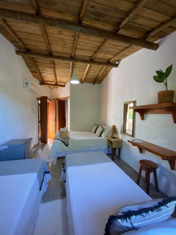 a bedroom with two beds and a wooden ceiling at Pousada Dendê Caraiva in Caraíva