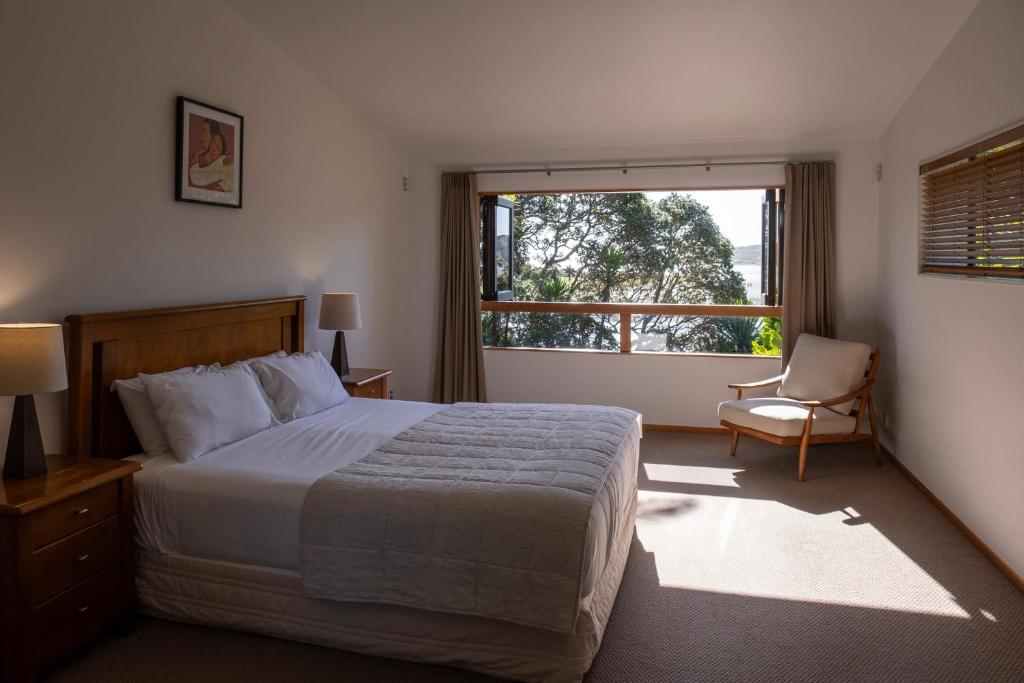 a bedroom with a bed and a window and a chair at Bow Street Apartments & Cottage in Raglan