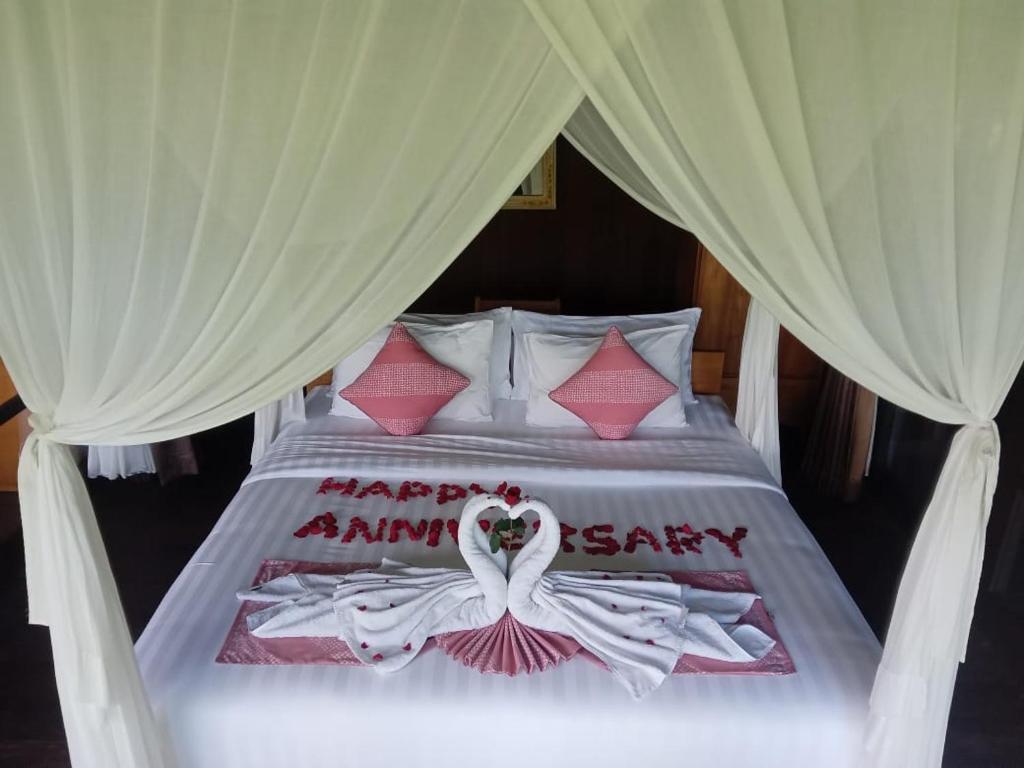 un letto con scritto sopra un felice anniversario di Villa Togog a Penebel