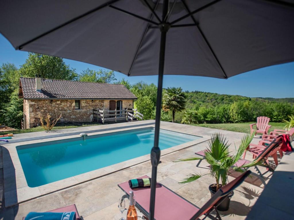 una piscina con sillas y una sombrilla junto a una casa en Le Tourel, en Saint-Cernin-de-lʼHerm