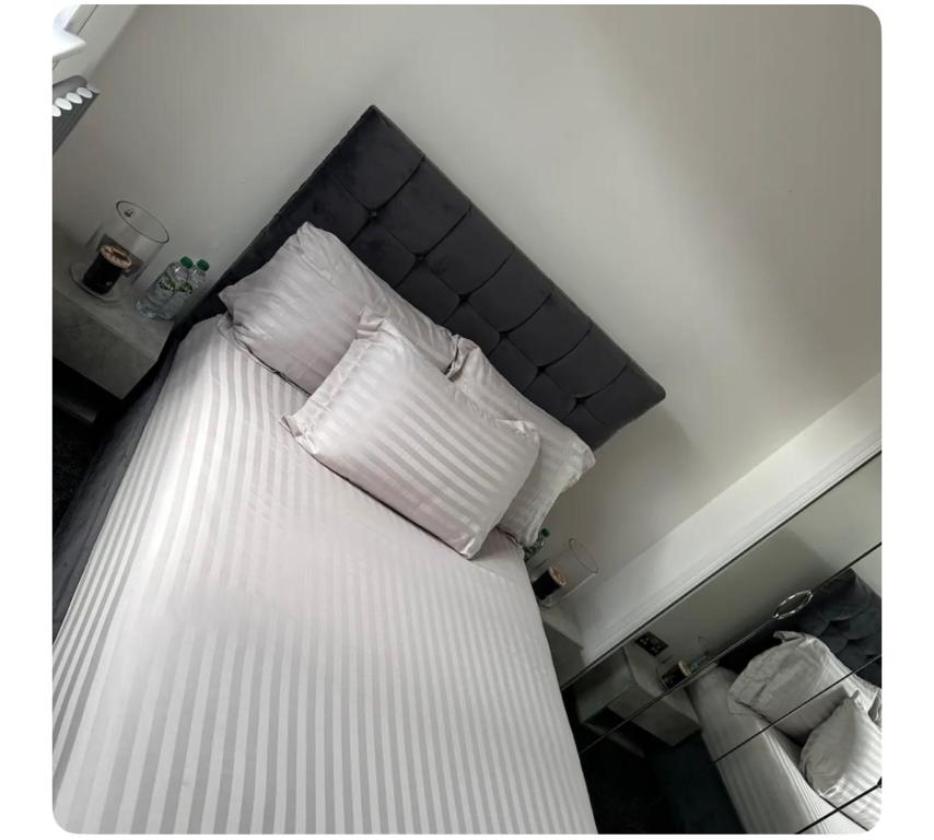 Una cama con sábanas blancas y almohadas. en Giles Apart, en Edimburgo