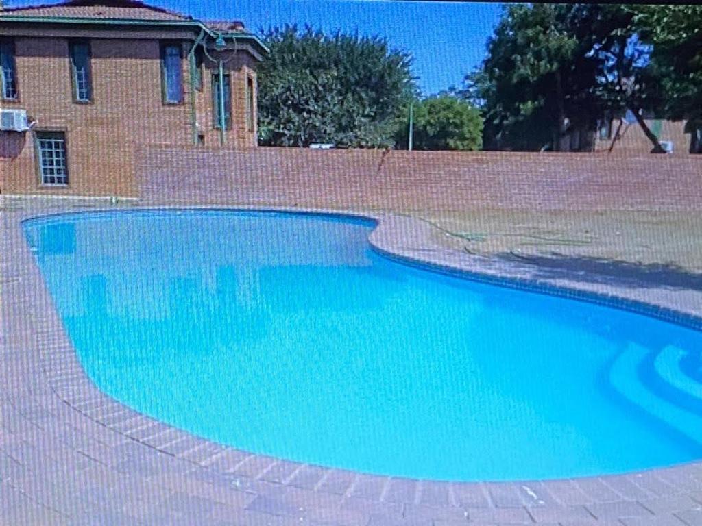 a large blue swimming pool next to a brick wall at Palm29 at Sunset Mews, Grand Palm - self catering appartment - Your Ideal Getaway for Work or Relaxation in Gaborone