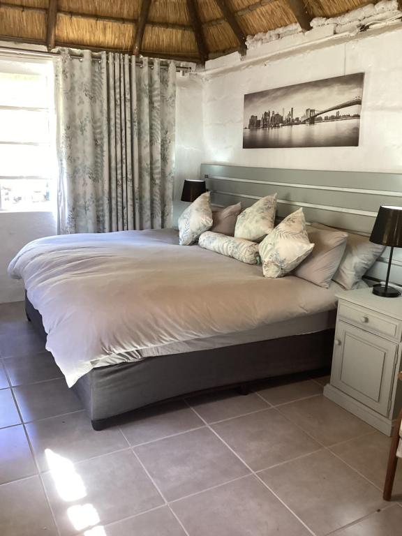 ein großes Bett mit Kissen darauf im Schlafzimmer in der Unterkunft Rosewood Cottage Apartment in Himeville