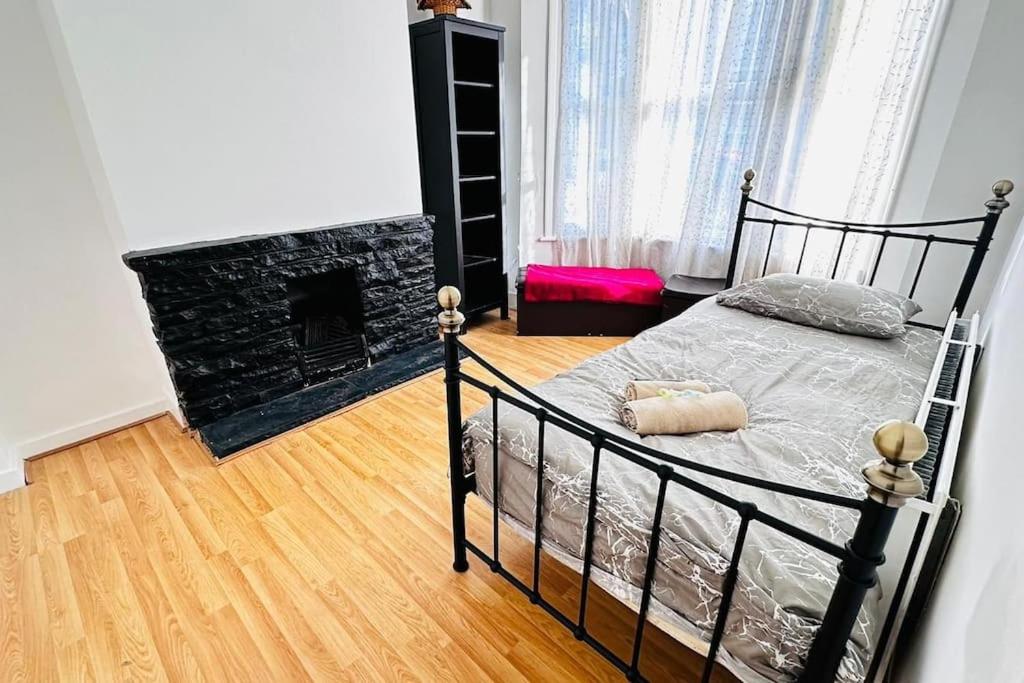 ein Schlafzimmer mit einem schwarzen Bett und einem Kamin in der Unterkunft 3 Bed House East London Home in London
