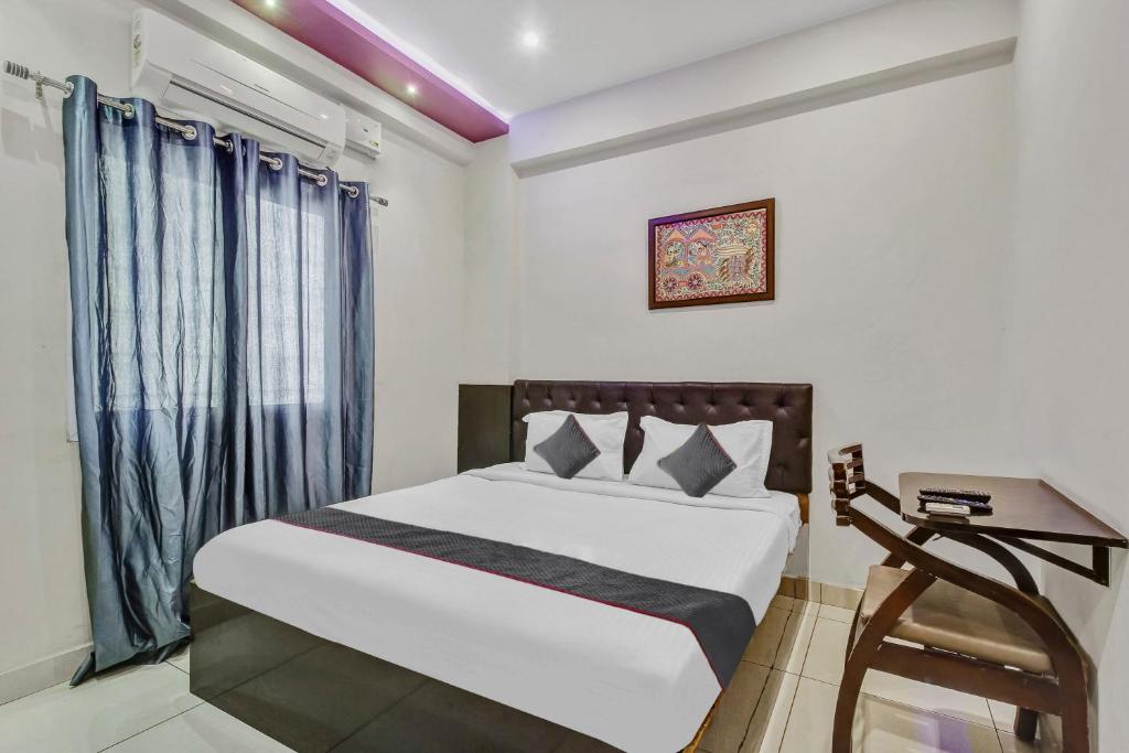 sypialnia z łóżkiem i oknem z niebieskimi zasłonami w obiekcie Collection O 1019 Galaxy Suites w mieście Hajdarabad