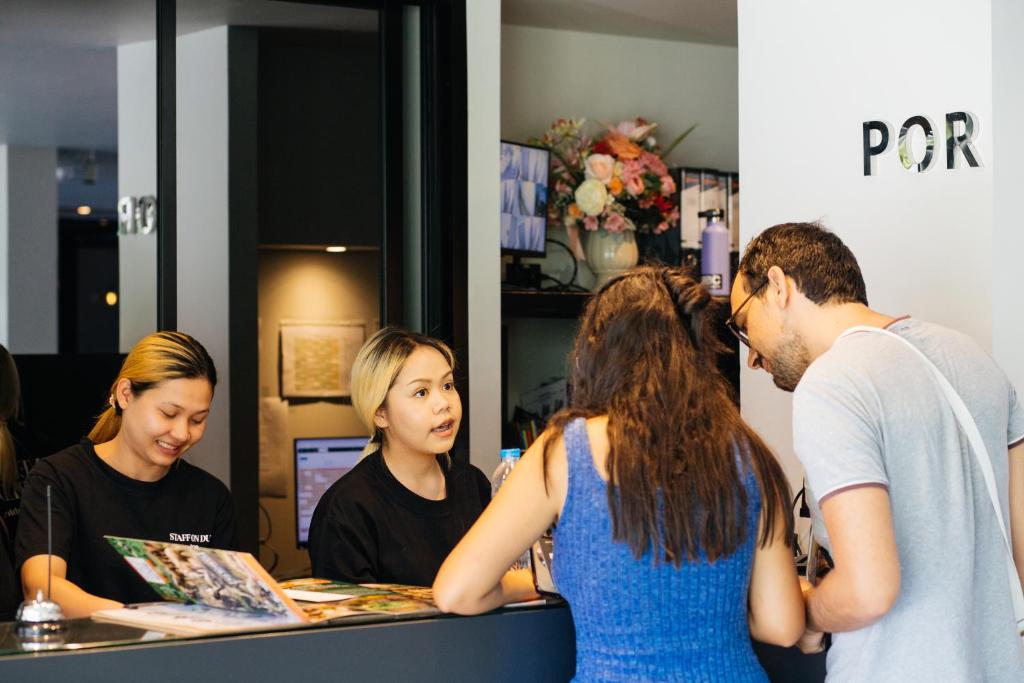 Several guests gather at the reception counter while staff handle check-in.