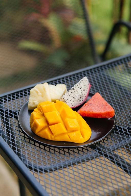 A close-up plate of tropical fruit on an outdoor mesh table.