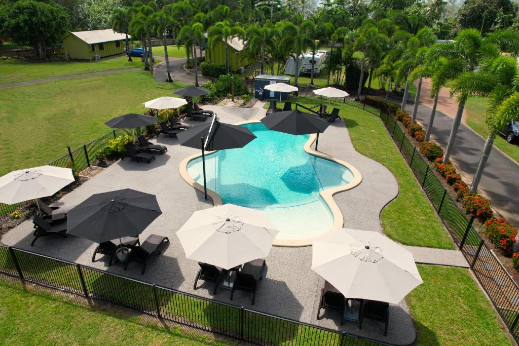 een uitzicht over een zwembad met parasols en stoelen bij Bali Hai Child Free Holiday Park Mission Beach in Mission Beach