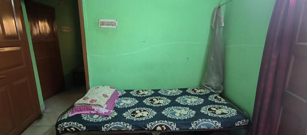 ein kleines Bett in einem kleinen Zimmer mit Tagesdecke in der Unterkunft Ladies pg in Kalkutta