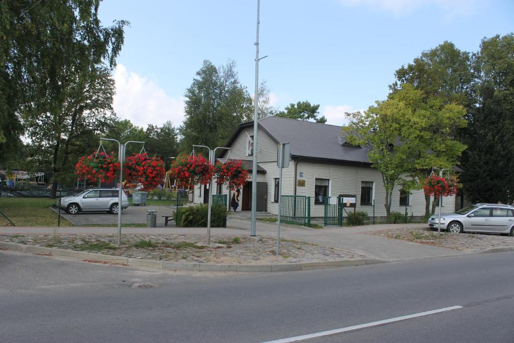 a building with red flowering trees in front of a street at Latvijas Sarkanā Krusta viesnīca in Rēzekne