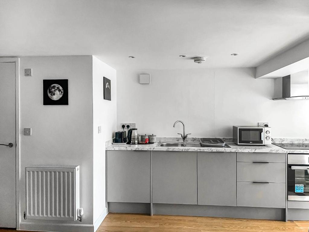 a white kitchen with a sink and a microwave at Honeymead - Uk46952 in Blackwood