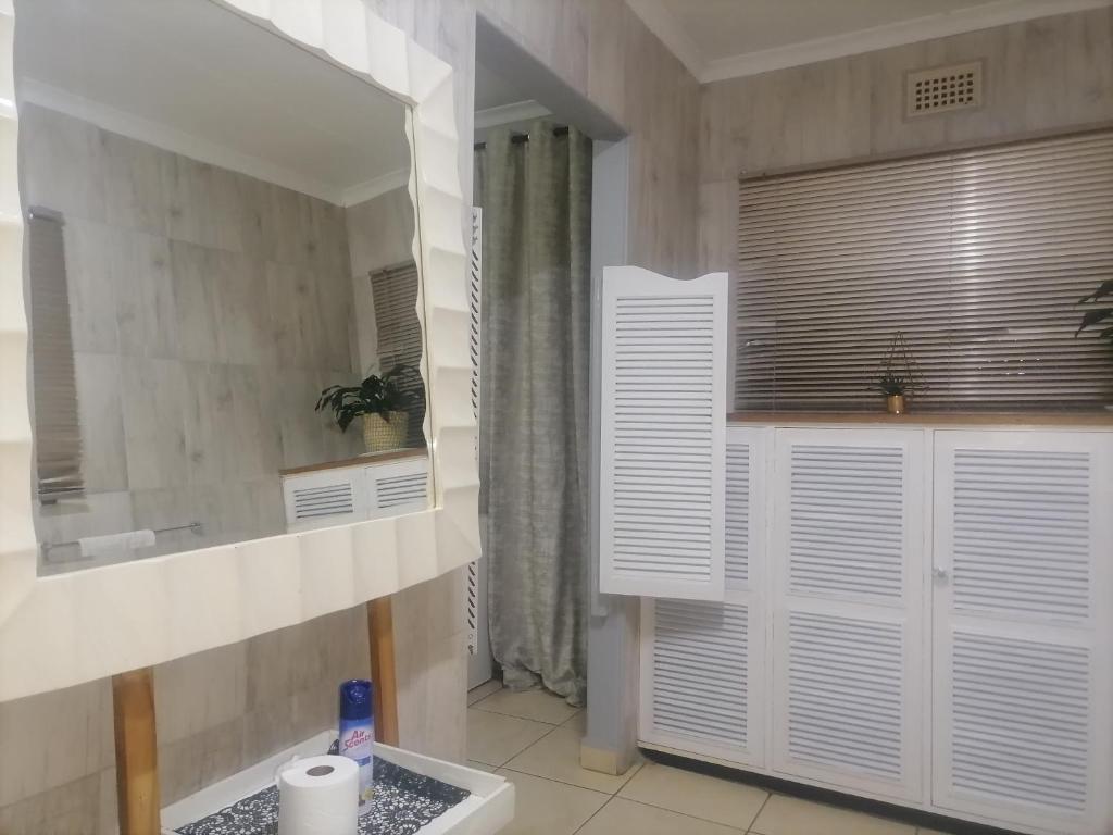 La salle de bains est pourvue d'un lavabo et d'un miroir. dans l'établissement Mbathos guesthouse, à Durban