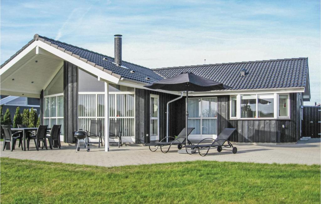 a house with a patio with chairs and an umbrella at Nice Home In Haderslev With 3 Bedrooms And Wifi in Årøsund