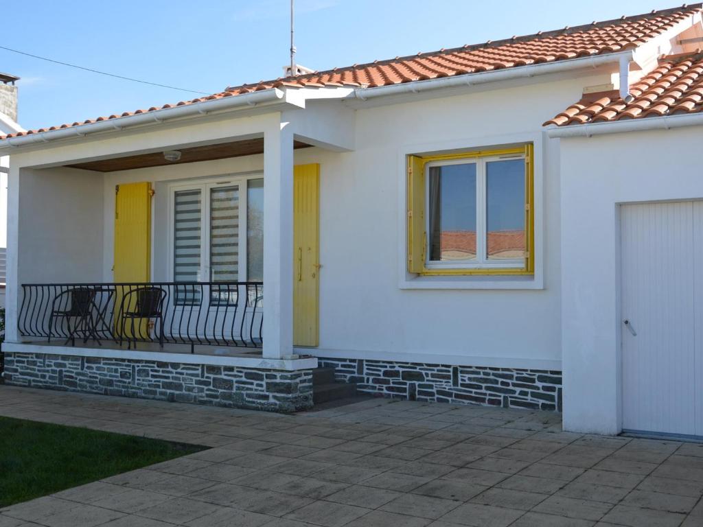 Cette maison blanche dispose d'une porte jaune et d'un balcon. dans l'établissement Maison rénovée avec jardin, proche plage, idéale famille, WiFi inclus - FR-1-323-535, à Saint-Hilaire-de-Riez