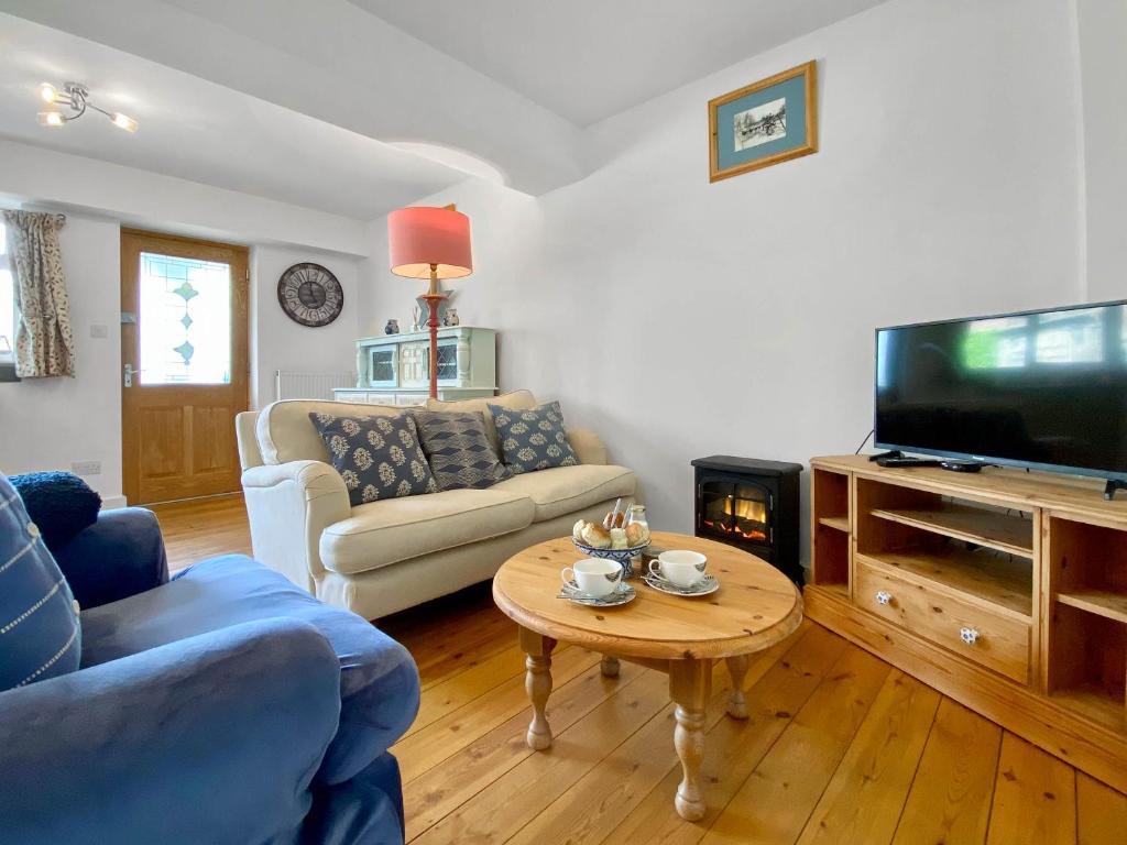 ein Wohnzimmer mit einem Sofa, einem Tisch und einem TV in der Unterkunft Anjou Bijou in Westbury-sub-Mendip