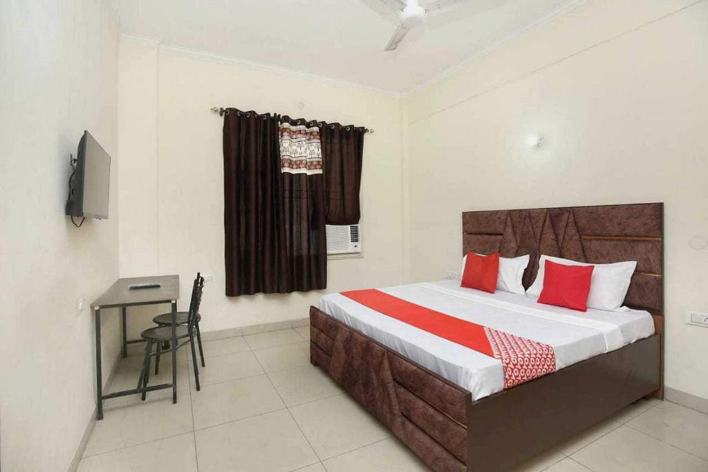 Sirhind的住宿－OYO Hotel Golden Crown，一间卧室配有一张带书桌的床和窗户。