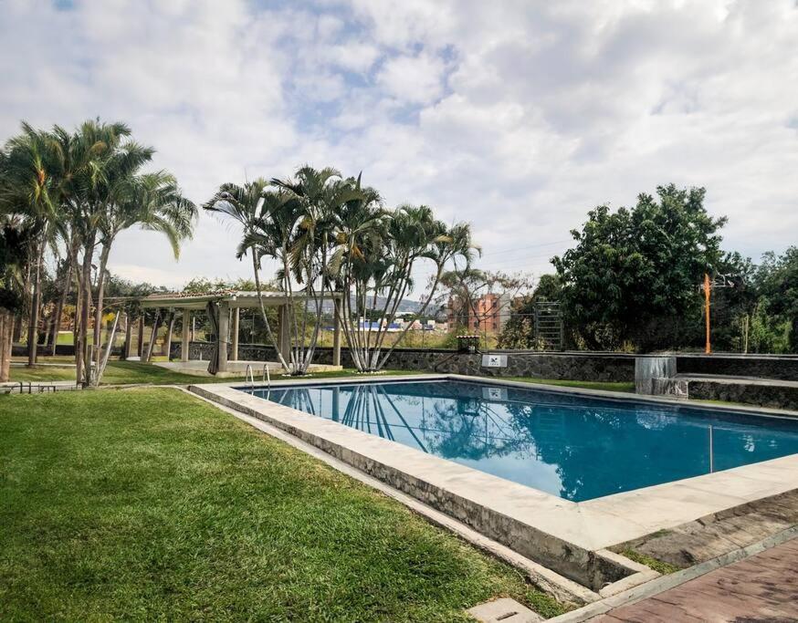 una piscina en un patio con palmeras en Cómoda Casa 3Hab: Piscina, Seguridad, Parking en Emiliano Zapata