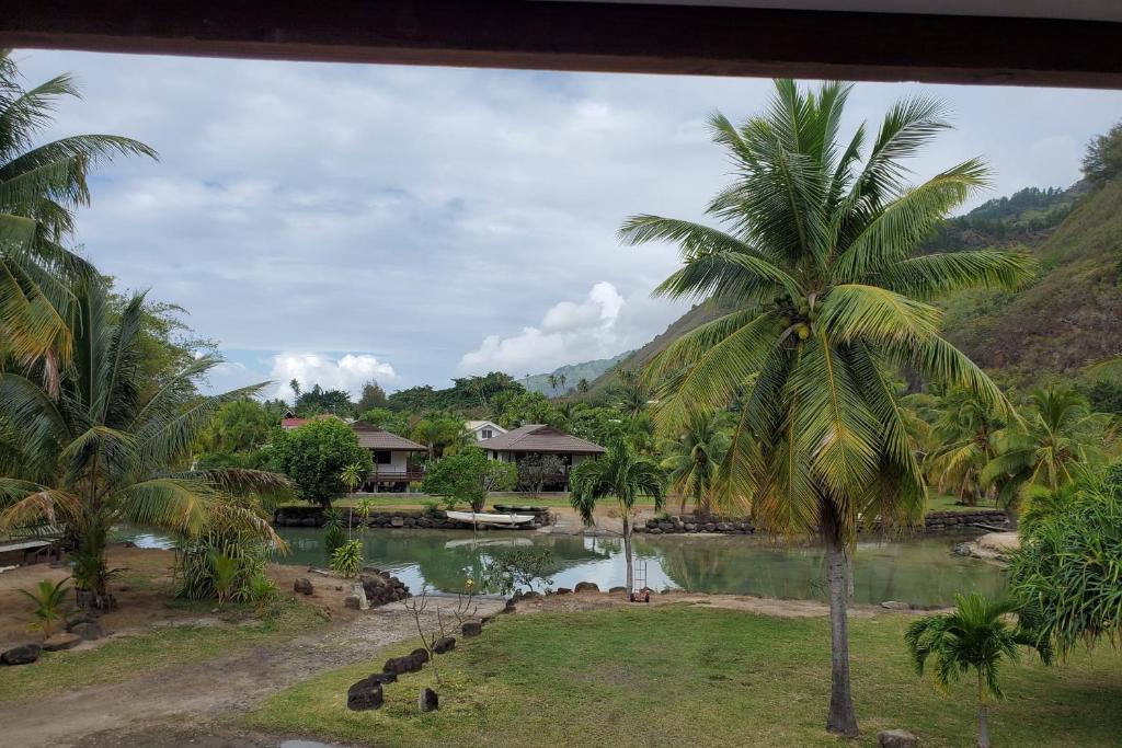 a view of a resort with a pond and palm trees at Faré Vaihere in Haapiti
