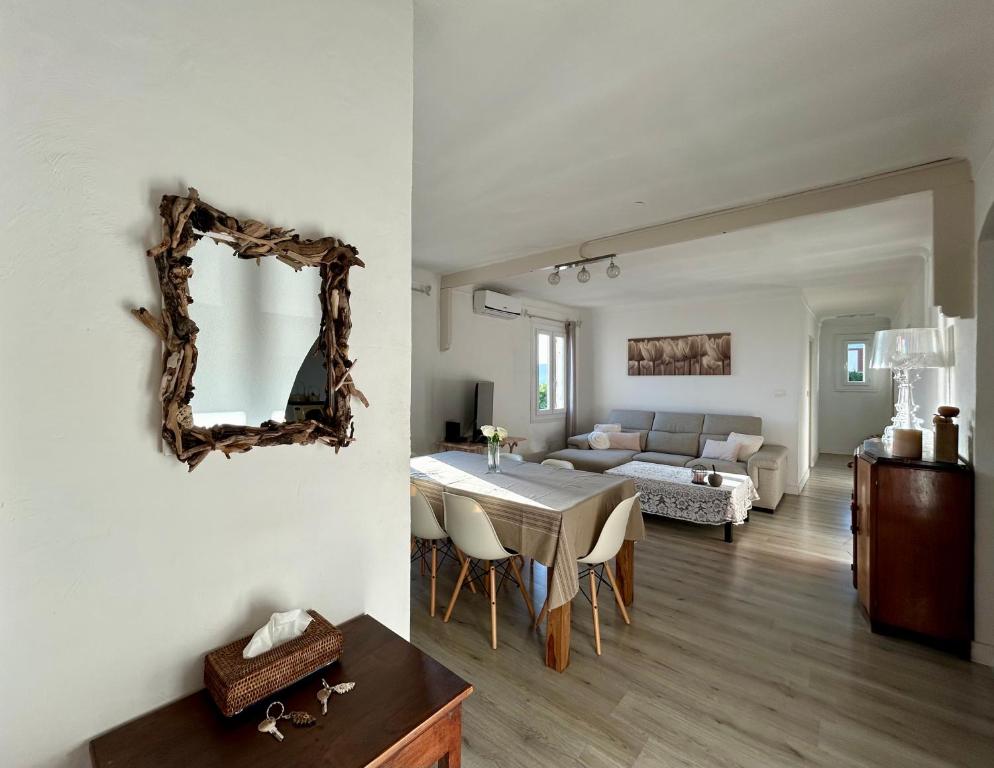 Sala de estar y comedor con mesa y espejo en Magnifique appartement devant la plage, en Propriano
