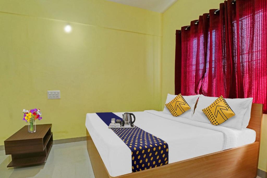 Habitación con cama con mesa y cortinas rojas en SPOT ON 70112 Sri Saptagiri Bording Lodging, en Bangalore