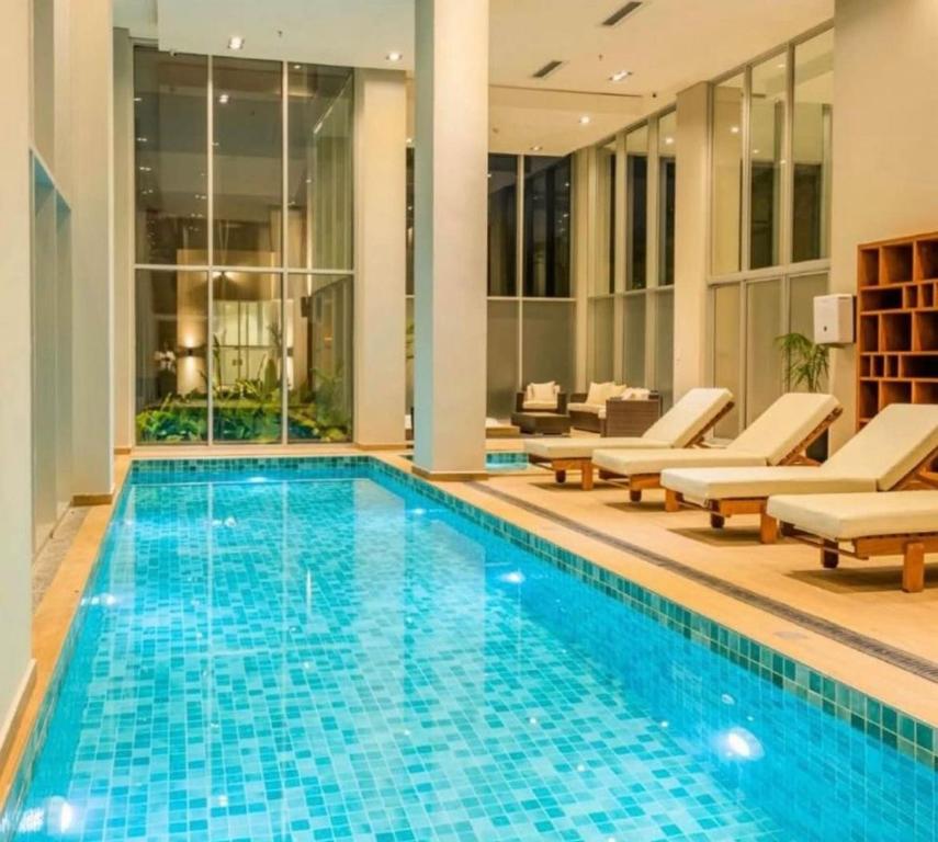 uma piscina num hotel com cadeiras e um sofá em Apto Lujoso, piscina climatizada, jacuzzi, gym. em Assunção