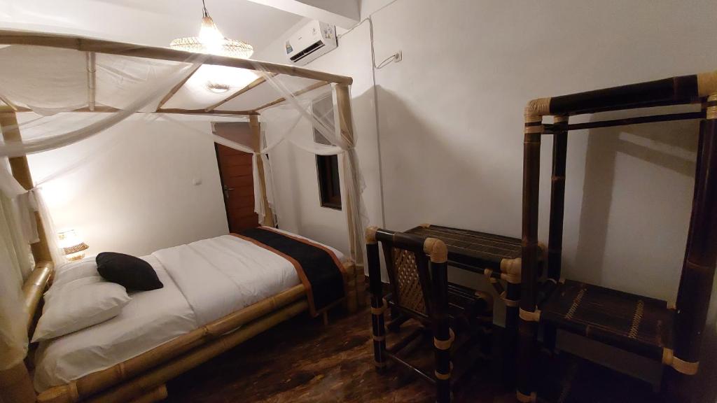 ein Schlafzimmer mit einem Himmelbett und einem Spiegel in der Unterkunft Ariwigangga Guest House in Krambitan