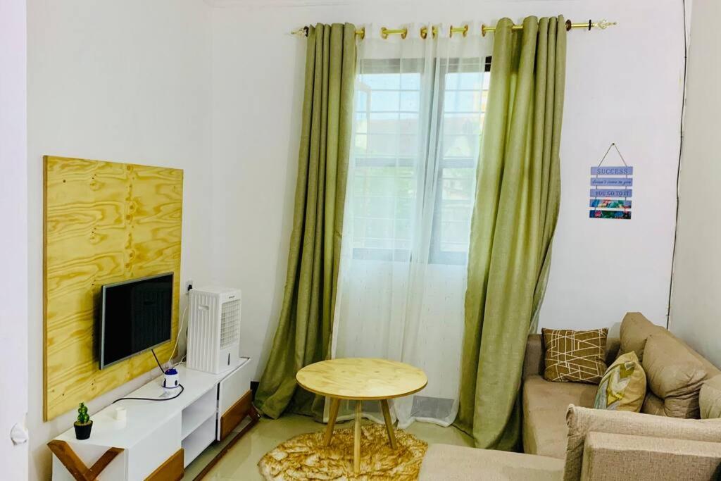 - un salon avec un canapé, une télévision et une table dans l'établissement Mikocheni Full House - 1 Bedroom, à Dar es Salaam