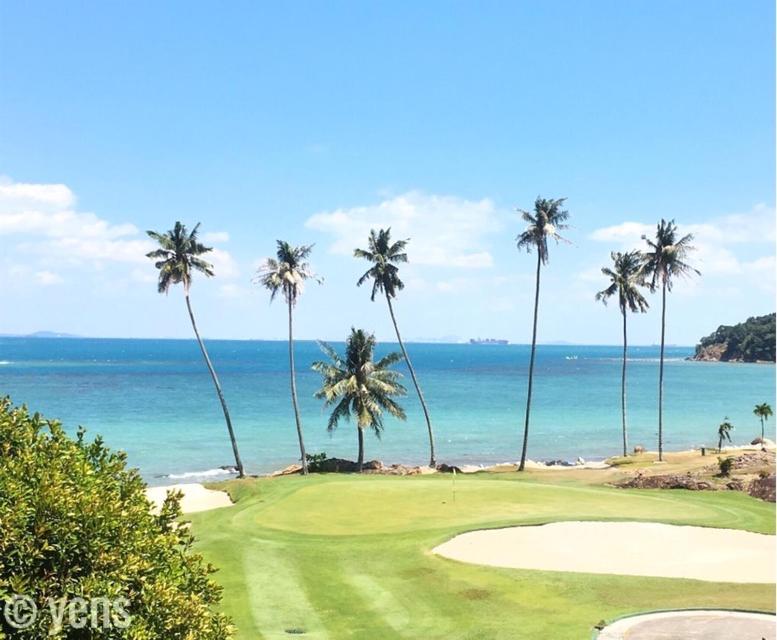 a golf course with palm trees and the ocean at Two Bedroom Apartment at The Nove, Nuvasa Bay, Nongsa 719 in Nongsa