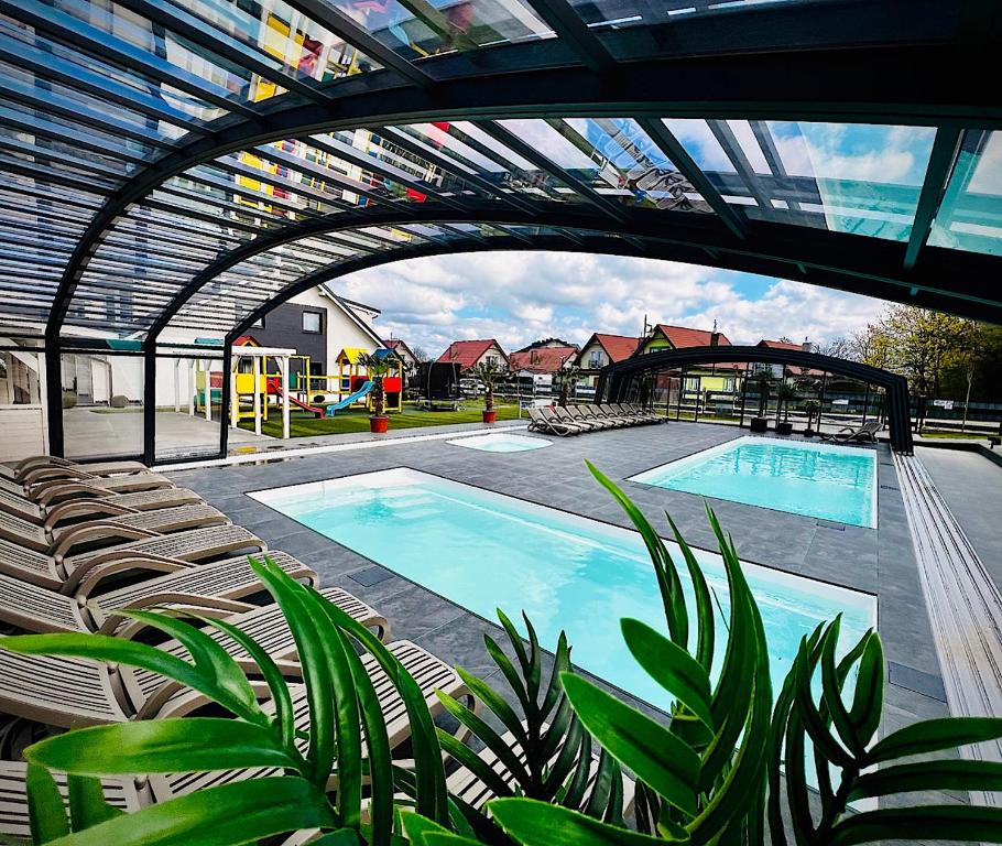 Una gran piscina con sillas y una sala de arte. en Domki Kotwica PARK Władysławowo - Trzy Baseny z Podgrzewaną Wodą pod Kopułą, en Władysławowo