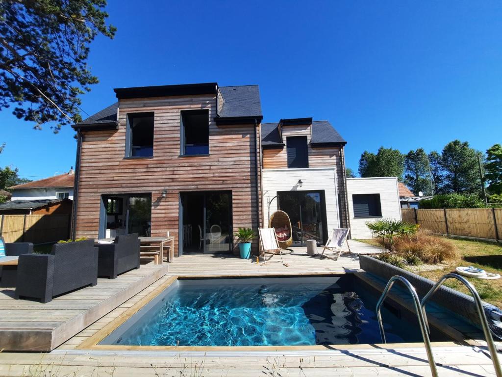 une maison avec une piscine en face d'une maison dans l'établissement RARE à Cabourg - Maison neuve avec piscine et jardin, à Cabourg