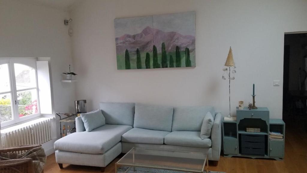 un soggiorno con divano e un dipinto sul muro di Le Nid des Rossignols ad Angers