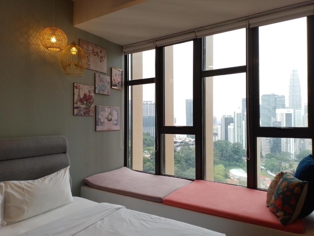 una camera da letto con due finestre, un letto e una panca rossa di Ceylonz Suite By ANA MALAYSIA a Kuala Lumpur