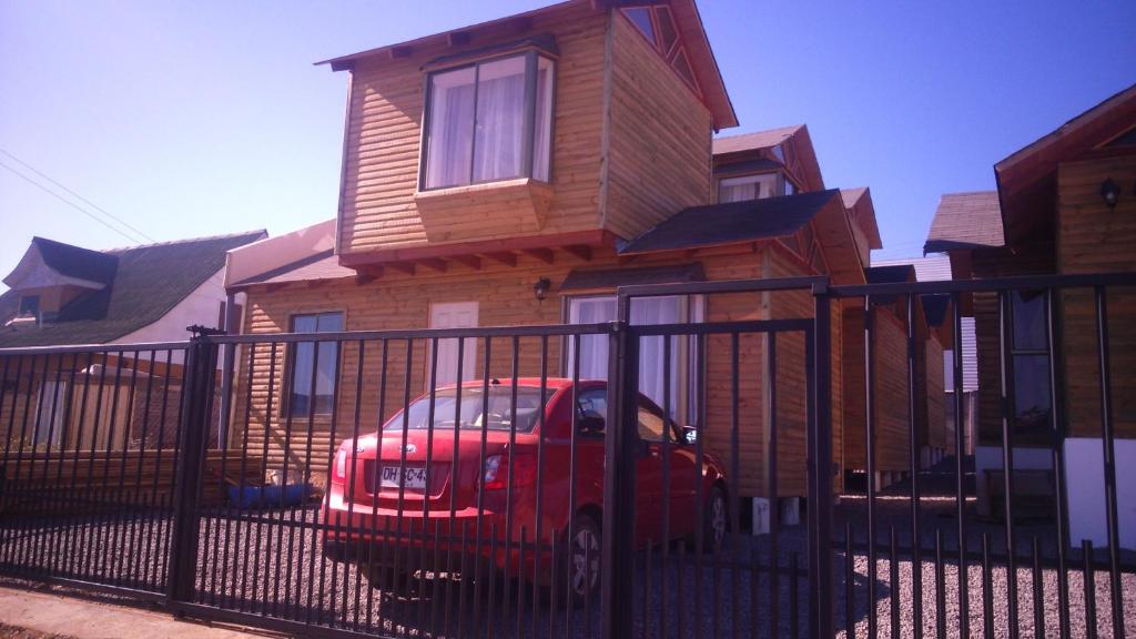 a red car parked in front of a house at Cabañas Antomai in Pichilemu