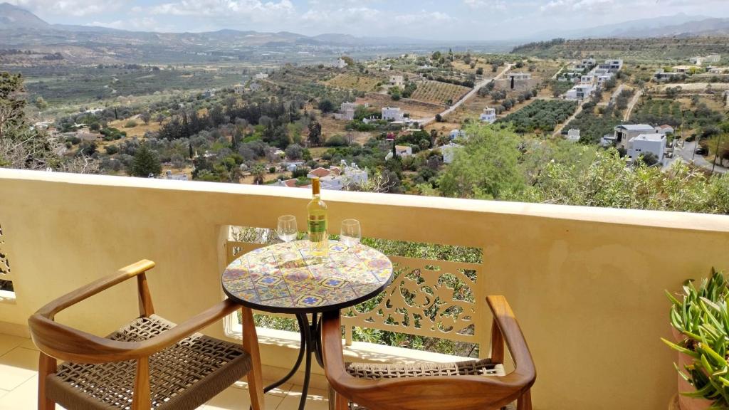 - Balcón con mesa y sillas y botella de vino en Malvazia Residence en Kamilari