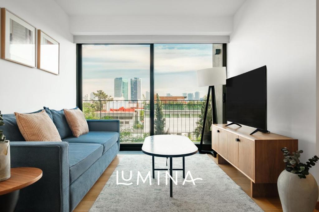 a living room with a blue couch and a large window at Lumina at Taman Condesa in Mexico City