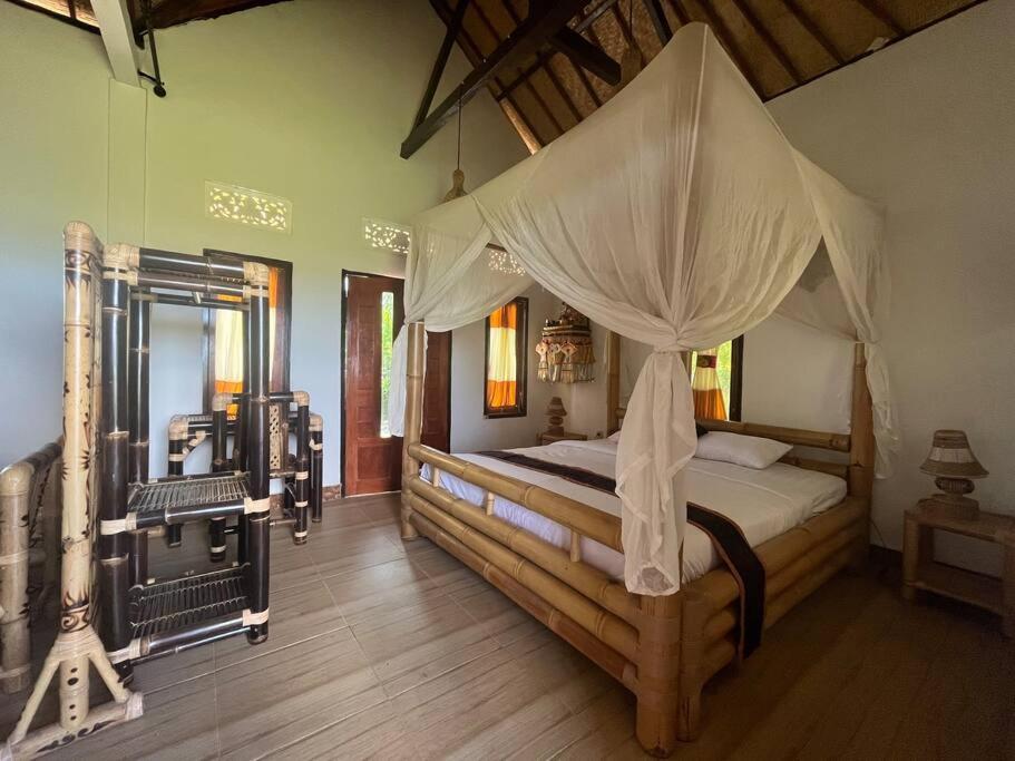 a bedroom with a bed with a canopy at Ariwigangga Garden Guest House in Krambitan