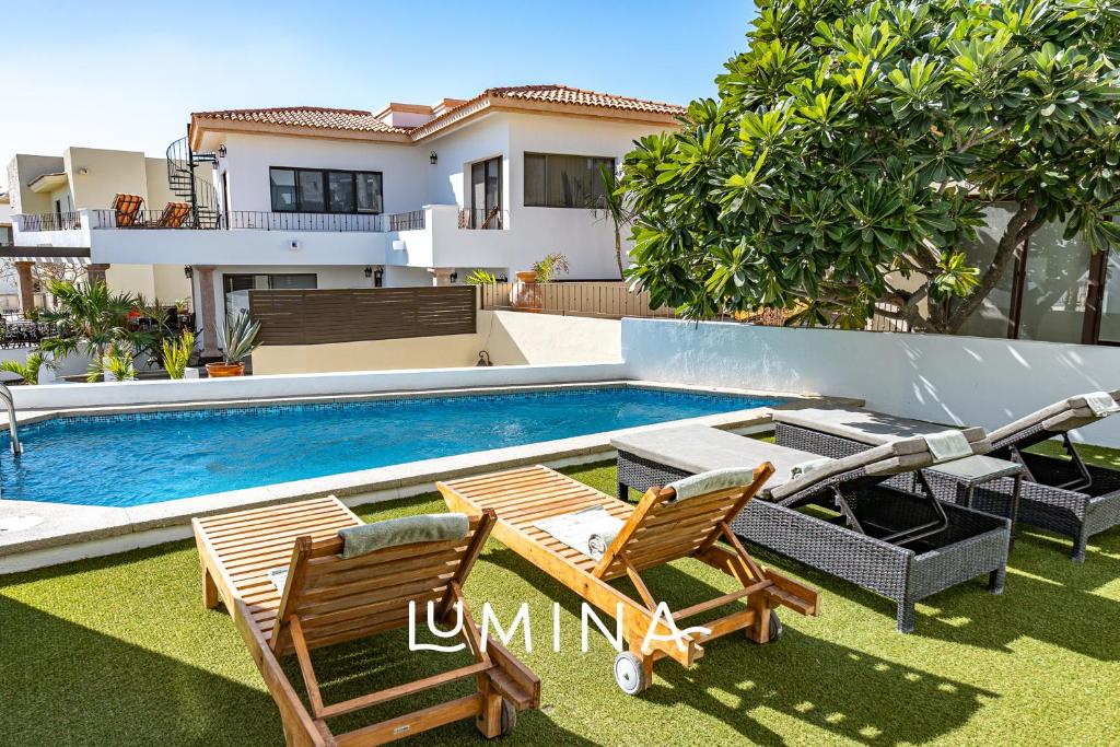 a swimming pool with two chairs and a house at Villa Bliss by Lumina in Cabo San Lucas
