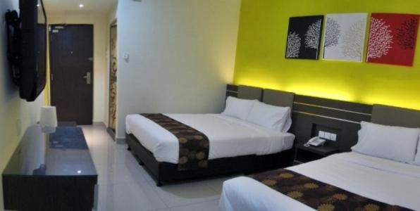 a hotel room with two beds and a desk at GM Holiday Hotel in Lumut