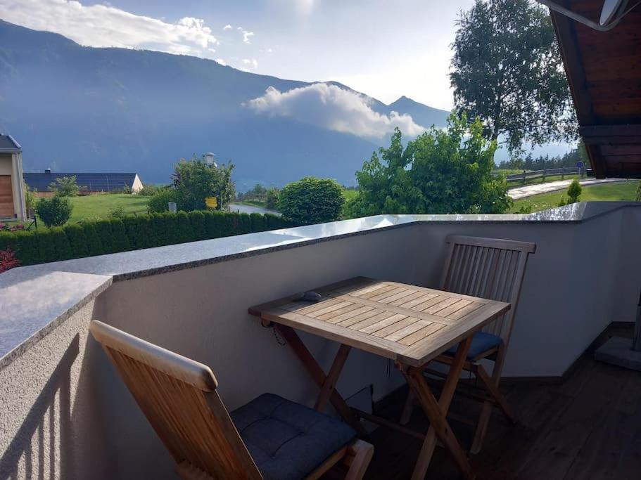a wooden table and two chairs on a balcony at Ferienwohnung Goldeckblick in Seeboden