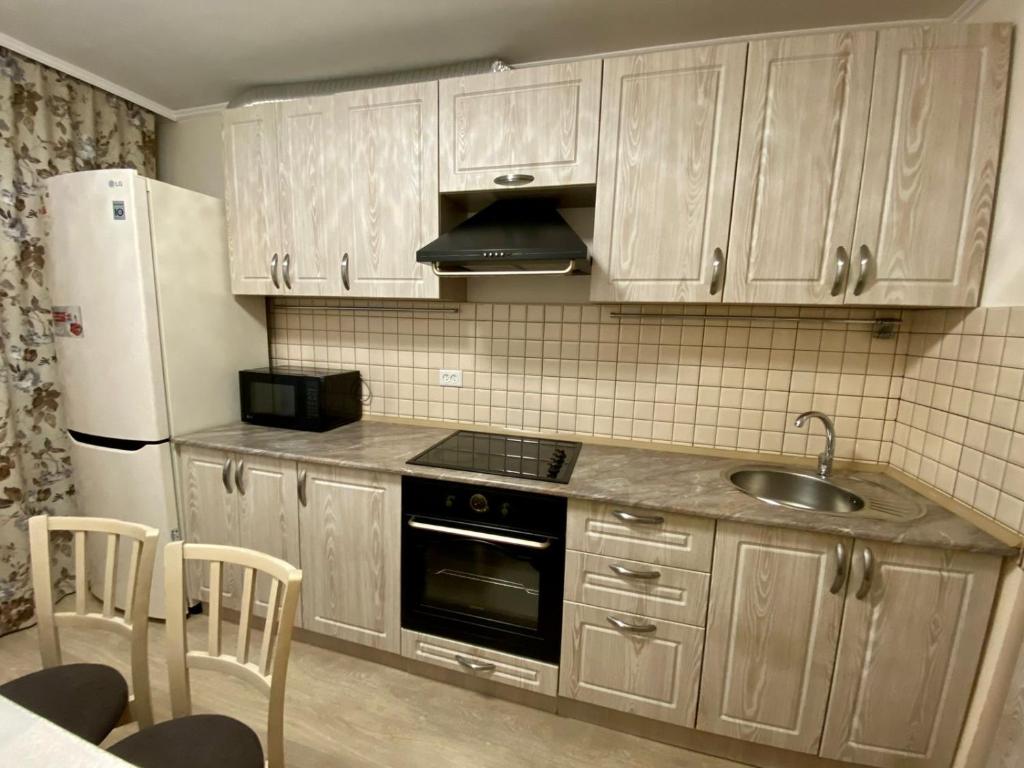 uma cozinha com armários de madeira, um lavatório e um frigorífico em UKA Comfort, 3х комнатная в центре. em Öskemen