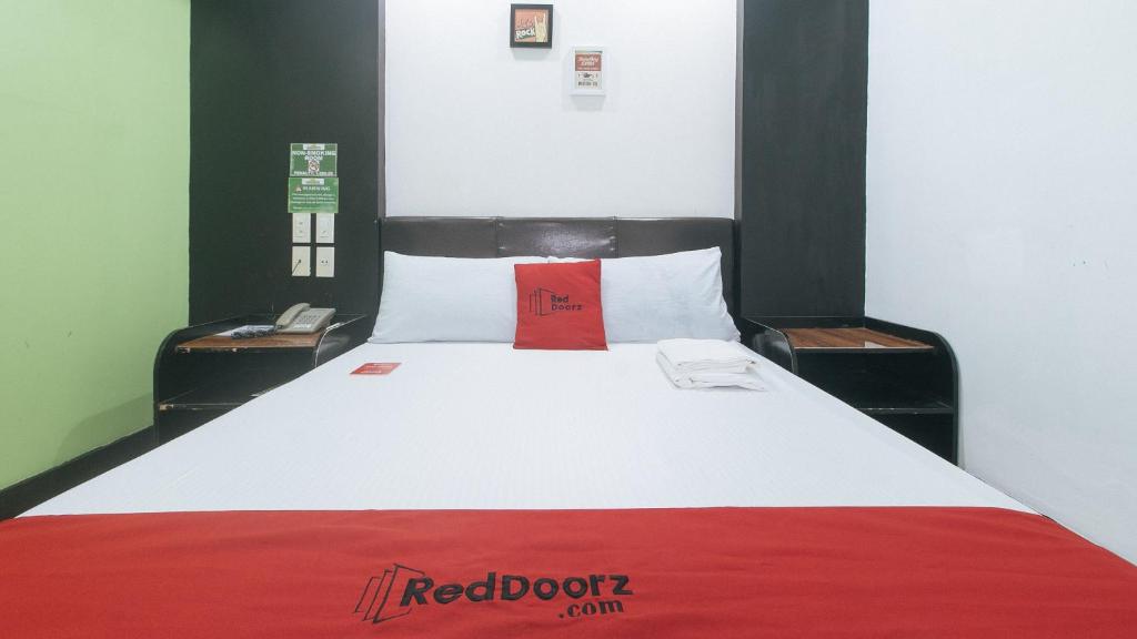 a bed with a red dot pillow on top of it at RedDoorz at Ranchotel Bayanan Alabang in Manila