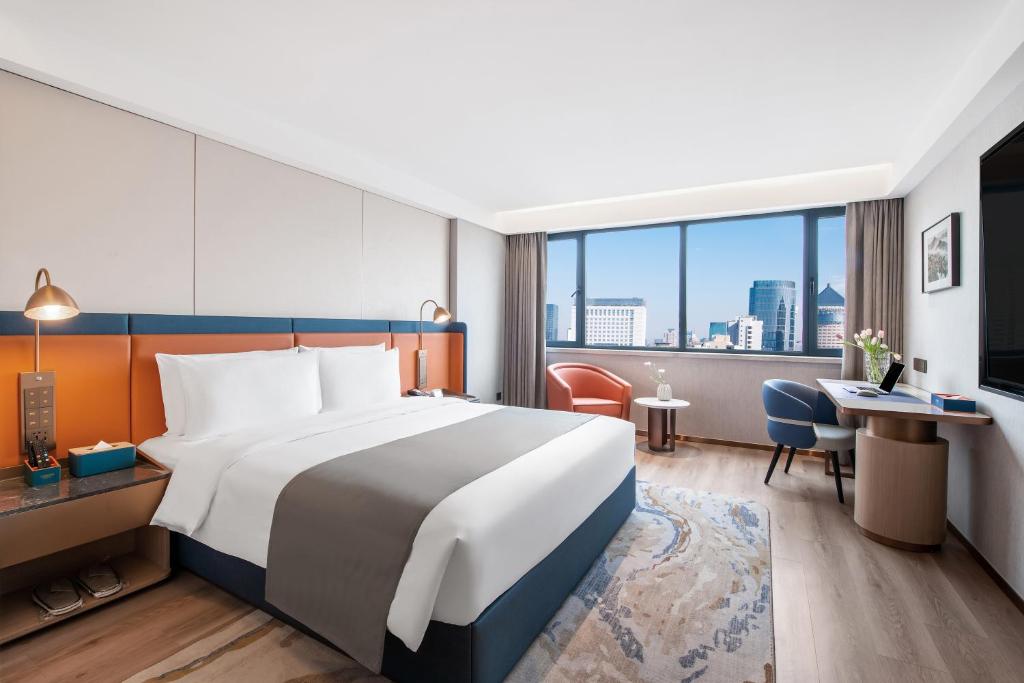 杭州市にあるLan'ou International Hotel - Wulin Square West Lakeの大きなベッドとデスクが備わるホテルルームです。