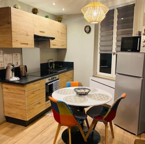 uma cozinha com uma mesa e cadeiras e um frigorífico em Hébergement Cosy avec terrasse Tropézienne em Le Chambon-Feugerolles