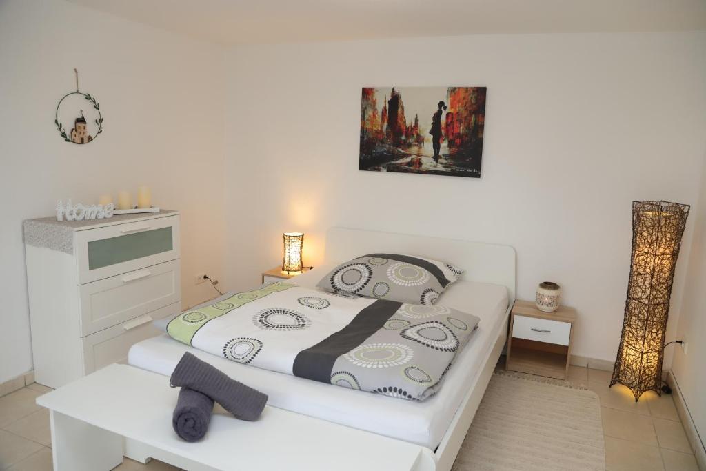 a white bedroom with a bed and a table at Zentrale, ruhige Wohnung in Innenstadt - Küche, Parkplatz, Terrasse, SmartTV, Netflix in Bitburg