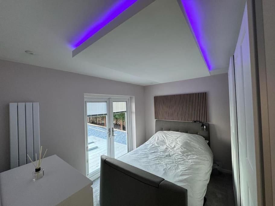 a bedroom with a bed and a couch and a purple light at The Tranquil Retreat in Llanfechell