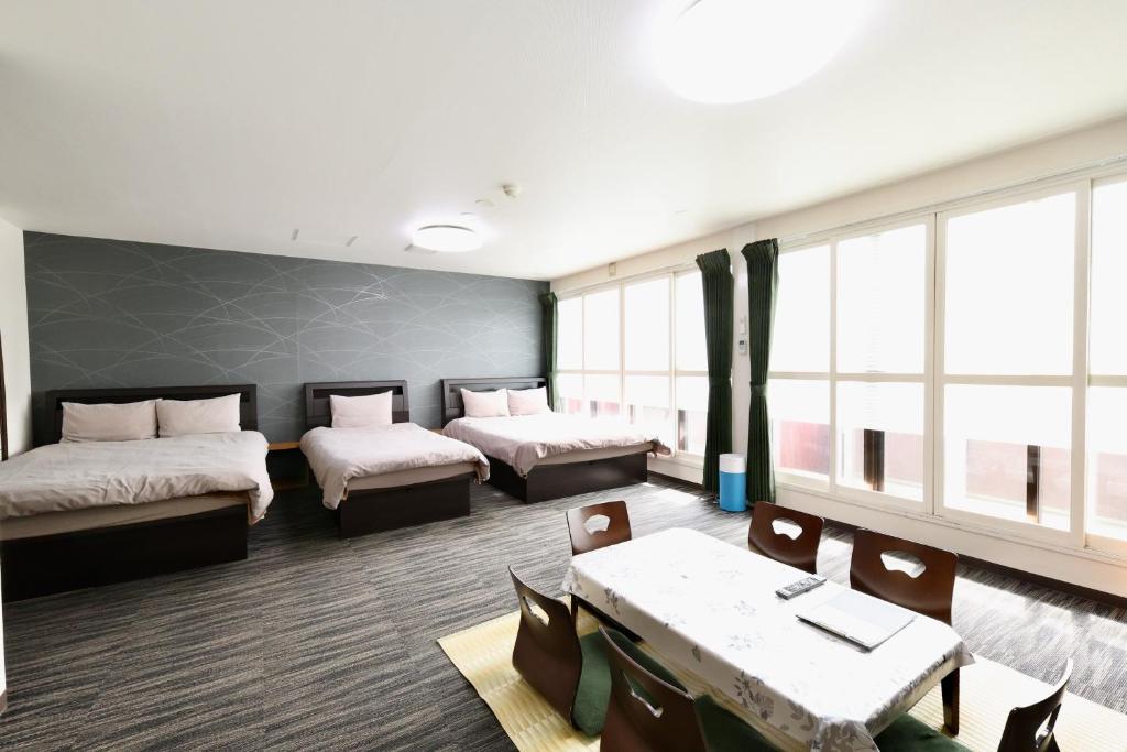 a room with two beds and a table and chairs at Apartment Susukino Hakuhou Building in Sapporo