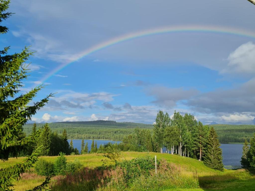 un arco iris sobre un campo y un lago en Swedish Paradise Garden & Lake Retreat 