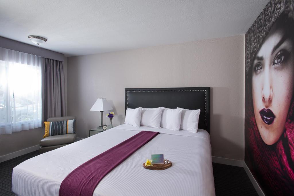 a hotel room with a bed with a woman on the wall at Hotel Iris - Mission Valley-San Diego Zoo-SeaWorld in San Diego