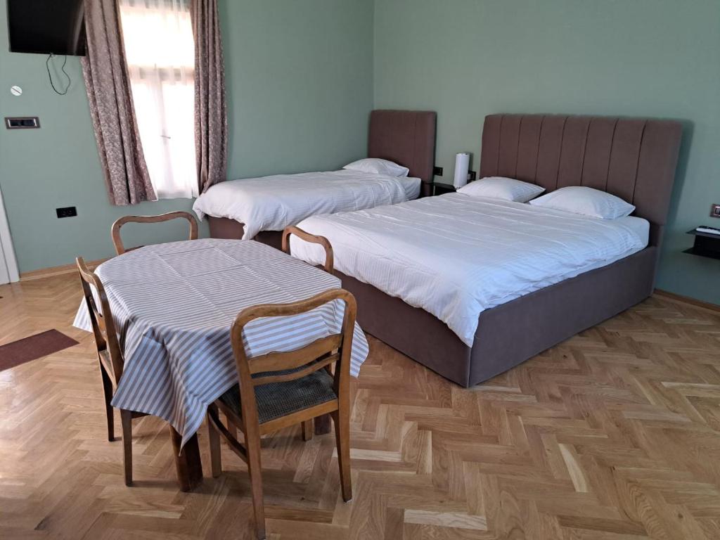 a bedroom with two beds and a table and chairs at Eagles Court - Orlovski Vrt in Staji°evo